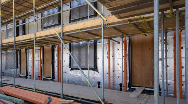 Scaffolding at a residential building under construction with windows and insulation sheets visible. - Photo by Mike van Schoonderwalt on Pexels