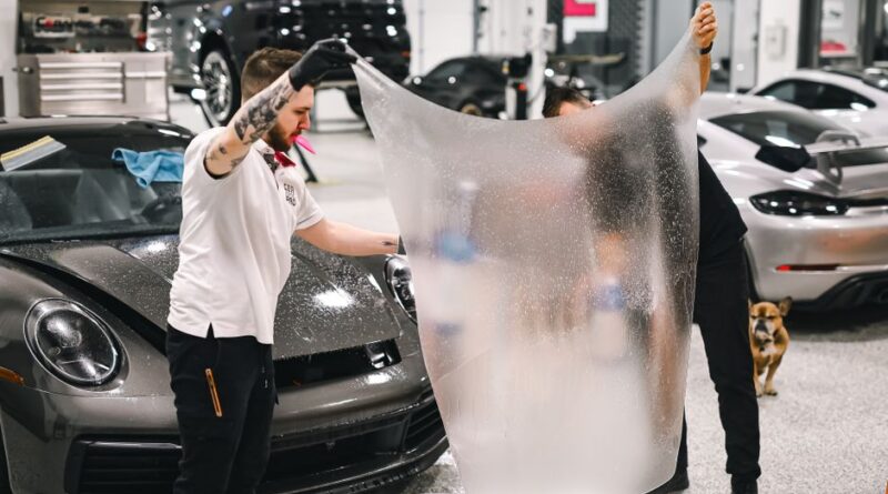 Two professionals applying protective film to a luxury car in a modern garage. - Photo by WAVYVISUALS on Pexels