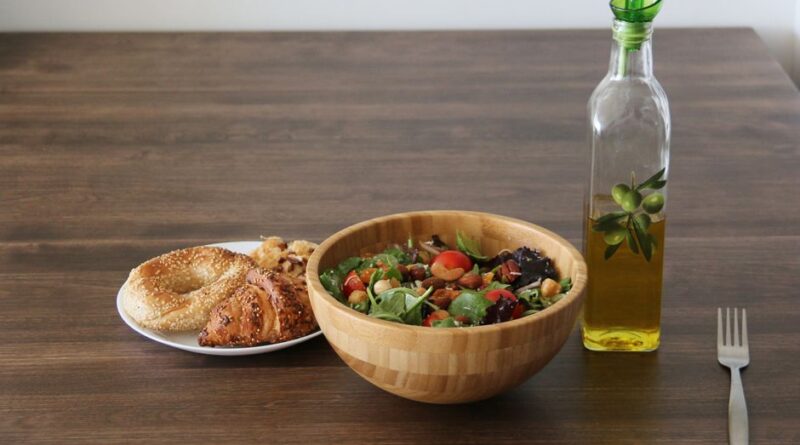 A vibrant vegetable salad with bagel and croissant, olive oil on a wooden table. - Photo by Ella Wei on Pexels